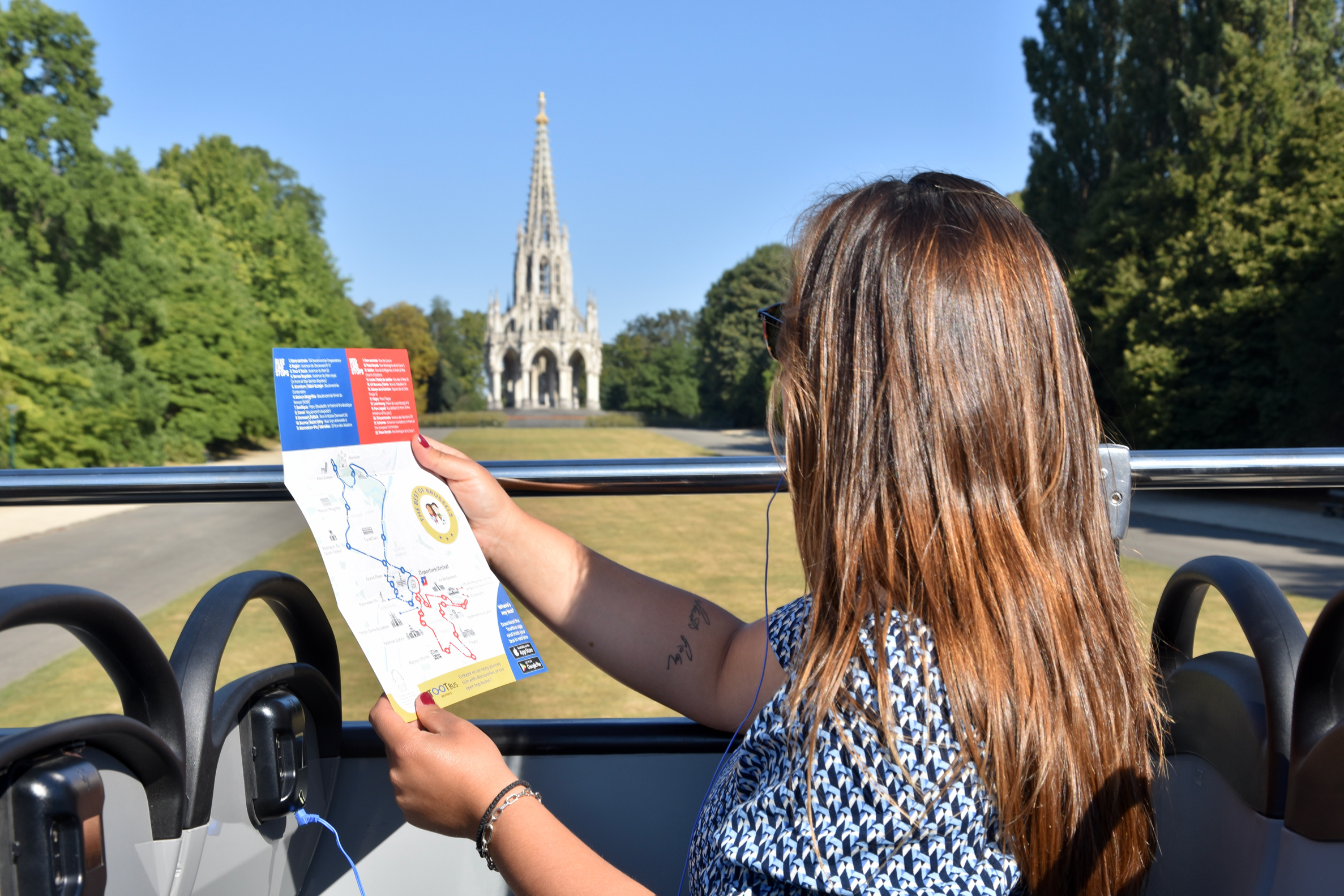 A woman on a Tootbus looks at a map in front of the Dynasty Monument in Laeken.