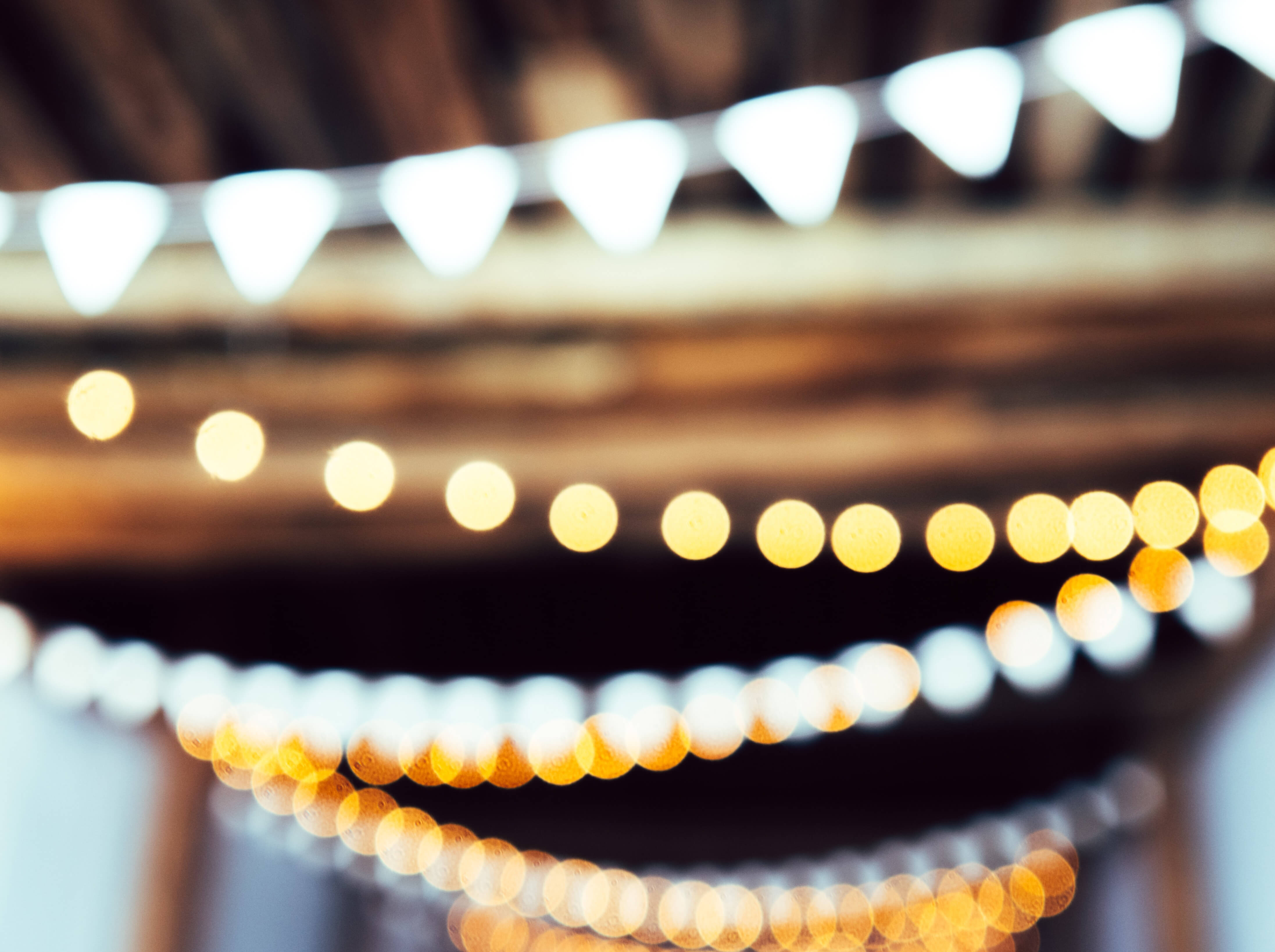 Vue floue en effet bokeh de guirlandes lumineuses festives et de fanions blancs suspendus, illustrant l'ambiance d'un événement privé.