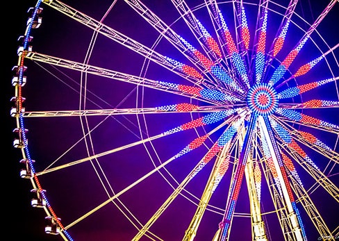 Close-up of the Paris Ferris wheel illuminated in blue, white, and red against a night sky.