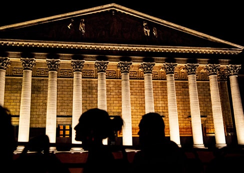 Vue nocturne de la Seine à Paris avec les reflets dorés des monuments illuminés, l'Institut de France à gauche et la Tour Eiffel au loin.