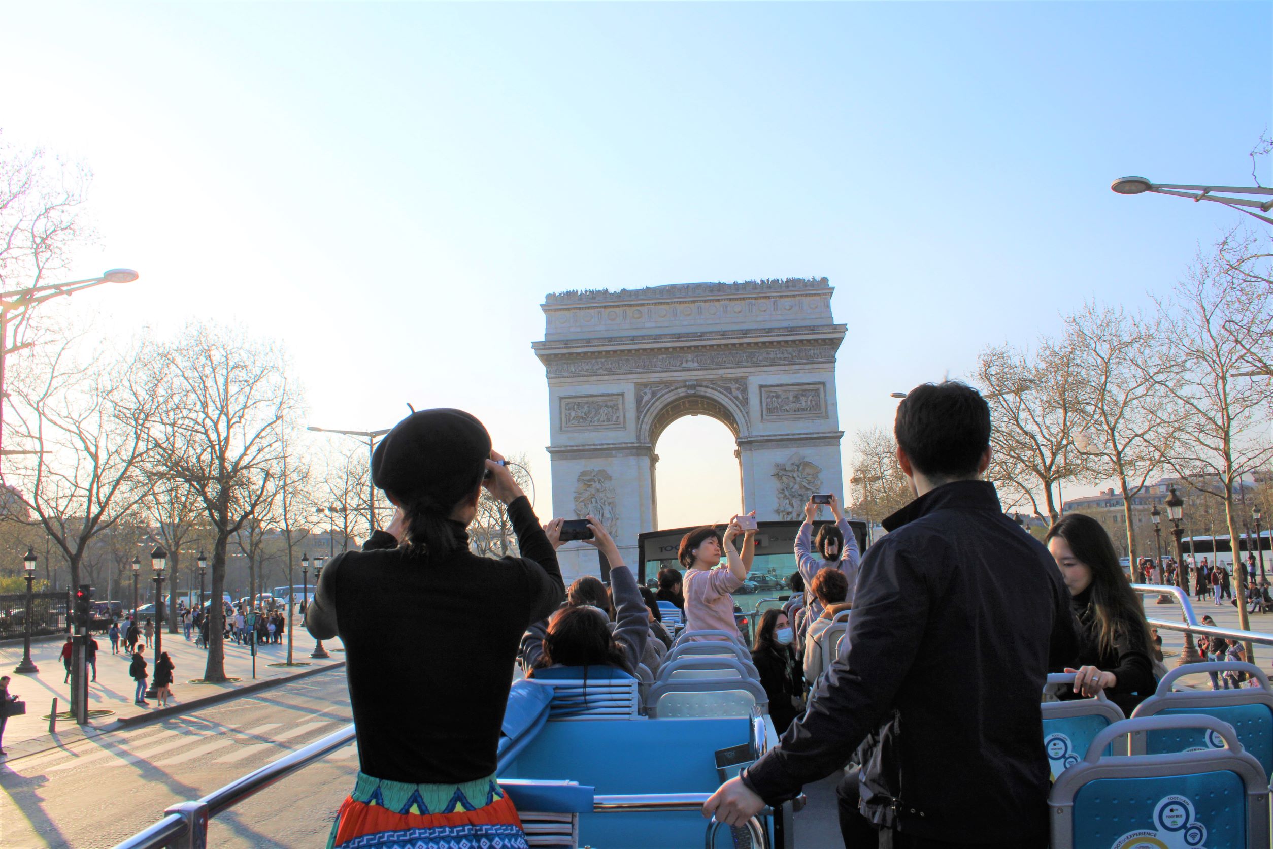 Los pasajeros toman fotos del Arco de Triunfo desde el piso superior abierto de un autobús Tootbus durante una ruta privada en París.