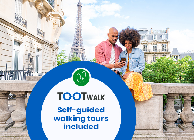 A couple sitting on a stone balustrade in Paris looks at a smartphone with the Eiffel Tower in the background, featuring a large blue and white badge in the foreground reading "TOOTWALK Self-guided walking tours included".