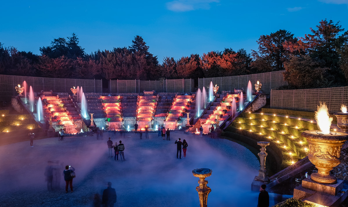 La cascada iluminada del bosquet de la Sala de Baile con efectos de niebla y antorchas encendidas durante las Grandes Aguas Nocturnas de Versalles.
