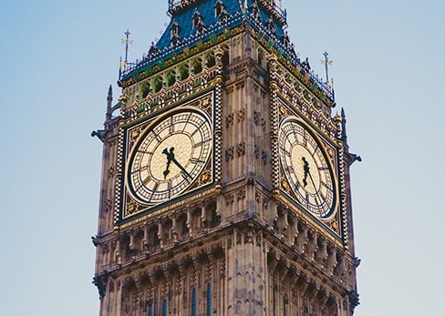 Close-up of the golden clock faces of the Big Ben tower in London under a clear sky.