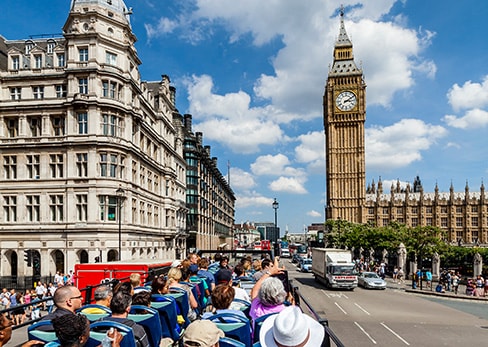 De nombreux touristes installés à l'étage supérieur d'un bus décapotable à Londres, admirant la tour de l'horloge du Big Ben par une journée ensoleillée.
