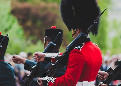 Gros plan de trois gardes royaux britanniques en uniforme traditionnel marchant avec leurs fusils lors d'un défilé militaire à Londres.