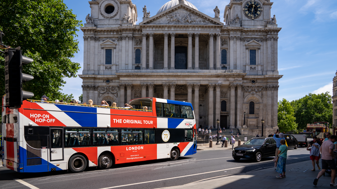 Autobús de dos pisos de Tootbus con los colores de la Union Jack circulando frente a la catedral de San Pablo en Londres en un día soleado.