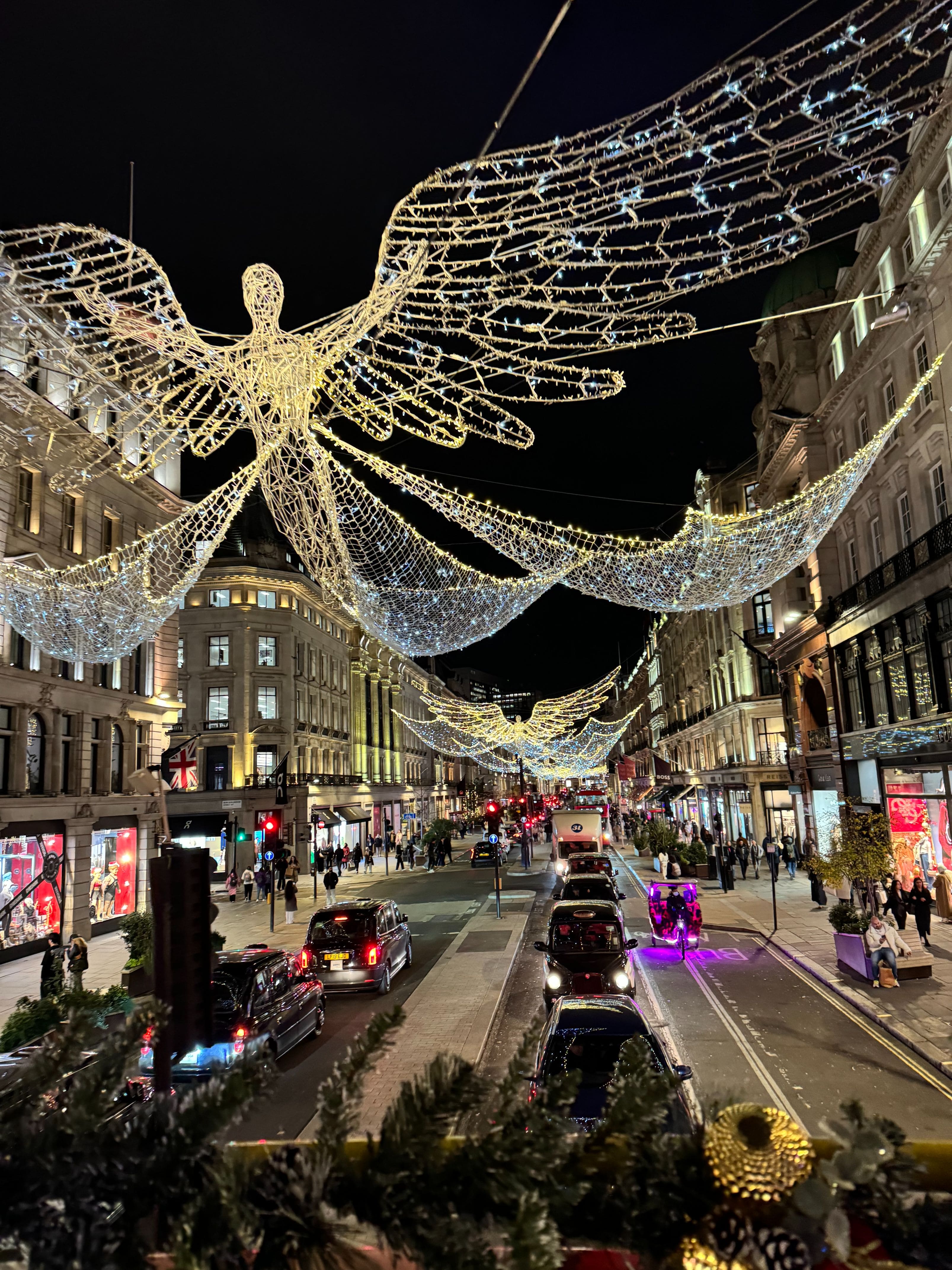 Grandes iluminaciones navideñas en forma de ángeles colgadas sobre Regent Street en Londres por la noche, vistas depuis lo alto de un autobús.