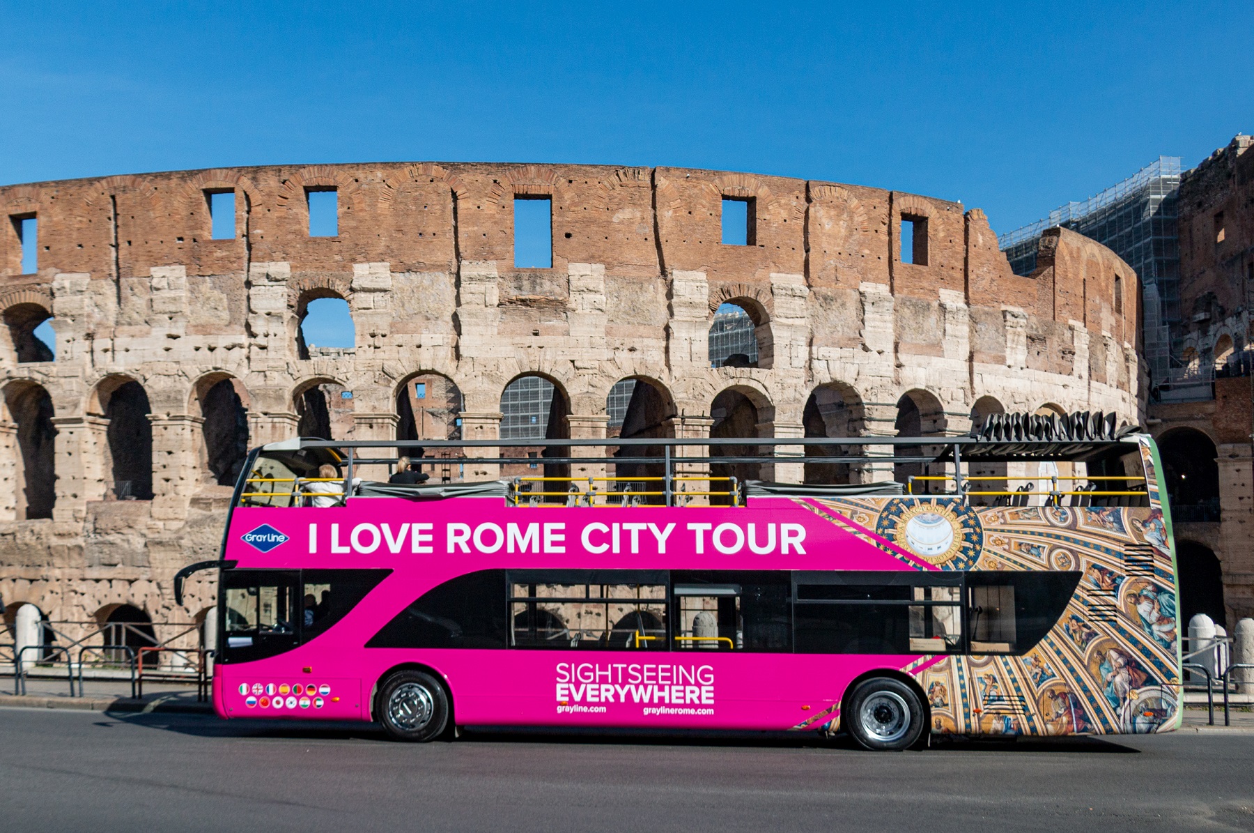 Pink "I Love Rome" sightseeing bus parked in front of the Colosseum in Rome.