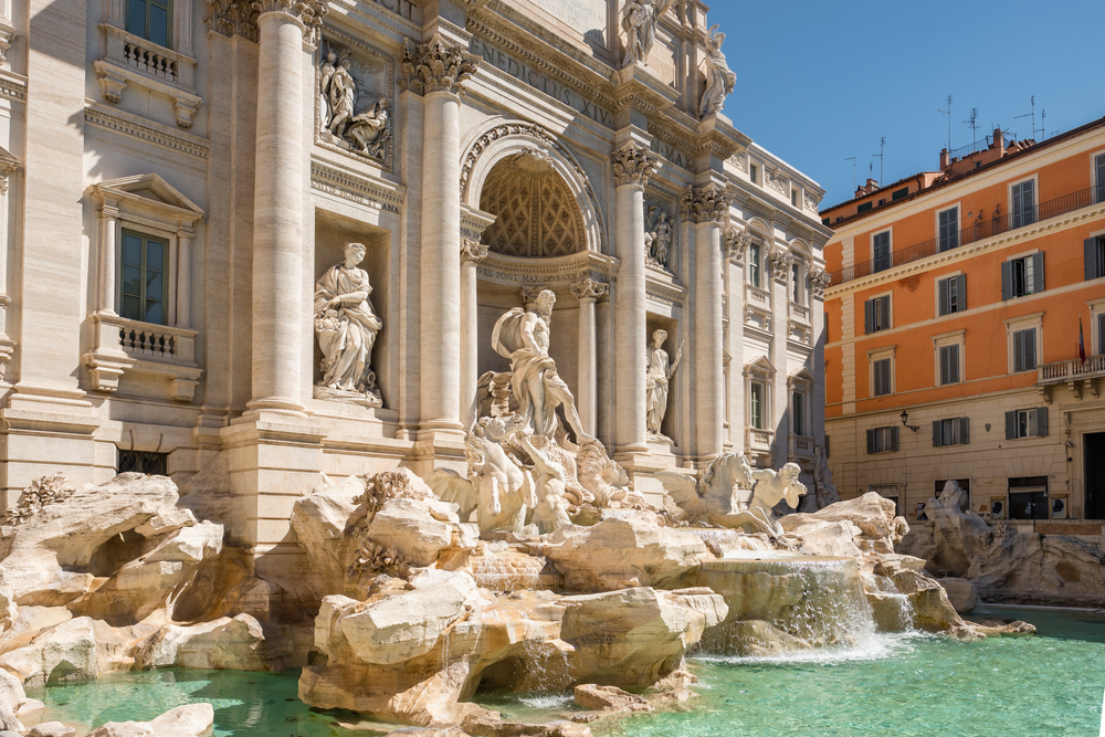 View of the famous Trevi Fountain in Rome under a sunny blue sky.