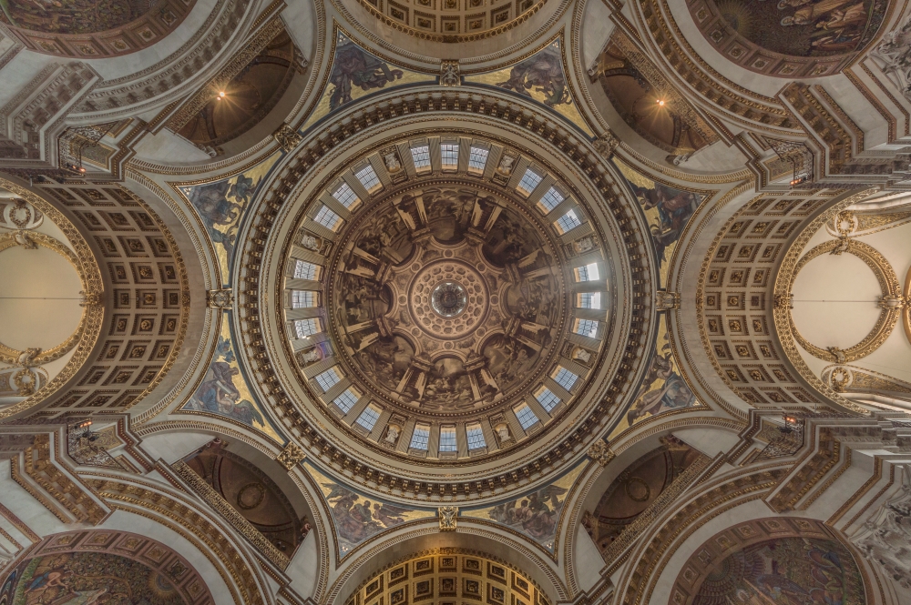 Spectacular low-angle view looking directly up into the ornate ceiling and frescoes of St Paul's Cathedral dome in London.