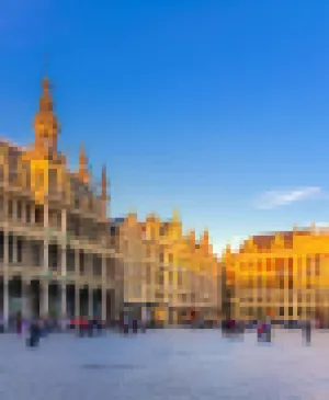 View of the Grand-Place in Brussels with its gothic and baroque buildings illuminated by the golden light of sunset under a blue sky.